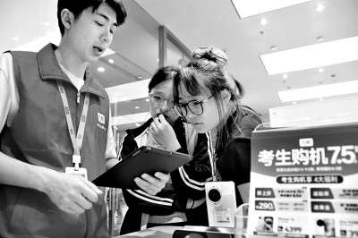云南省蒙自市一店內(nèi)工作人員為今年高考考生講解手機“國補”政策。薛瑩瑩攝:光明圖片.jpg